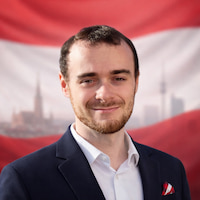 Porträt von Thomas Bella MSc BSc vor blauem Himmel, freundlich lächelnd mit kurzem Bart und sportlicher Jacke - Tech Lead Cyber Security aus Österreich.